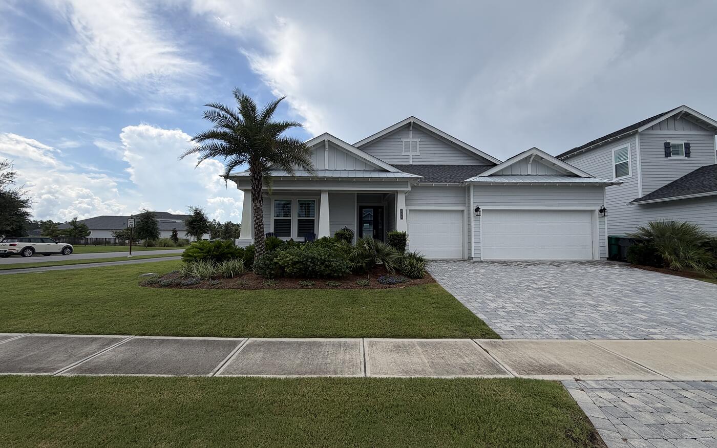 A coastal home with palms and a clean paver drive after a maintenance visit