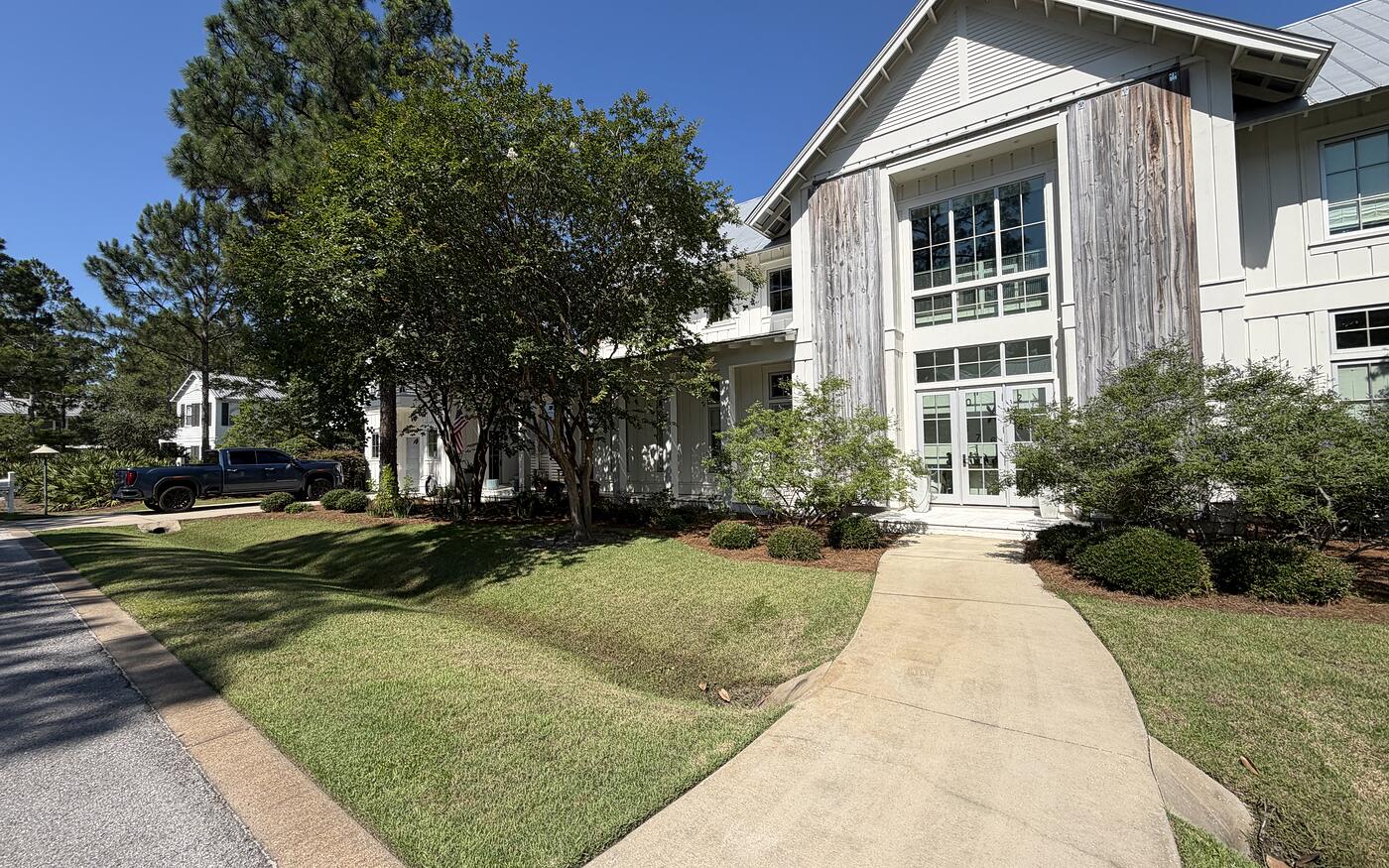 A large coastal home with a walkway and cut lawn